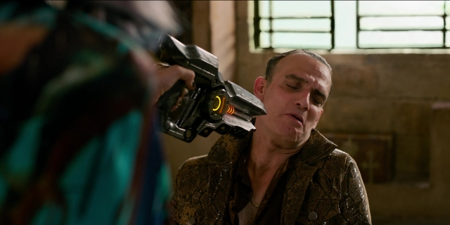 Wide shot frame from Men in Black International — room, hand, gun