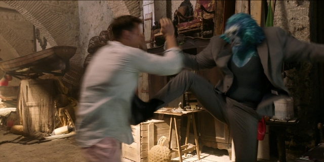 Wide shot frame from Men in Black International — room, table, suit