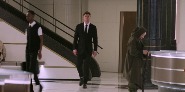 Wide shot frame from Men in Black International — walking, door, coat