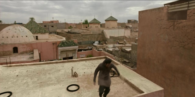 Wide shot frame from Men in Black International — walking, person, window