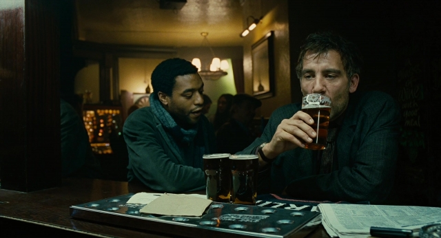 Wide shot frame from Children of Men — sitting, table, beer