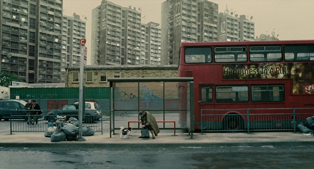 Wide shot frame from Children of Men — sitting, street, dog