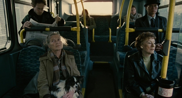 Wide shot frame from Children of Men — sitting, street, hat