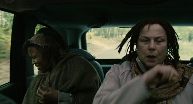 Medium shot frame from Children of Men — sitting, street, car
