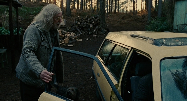 Wide shot frame from Children of Men — sitting, standing, door