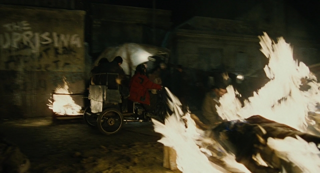 Wide shot frame from Children of Men — standing, room, fire
