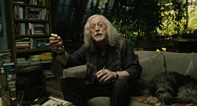 Wide shot frame from Children of Men — sitting, book, room