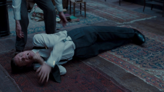 Wide shot frame from The King's Speech — sitting, standing, table