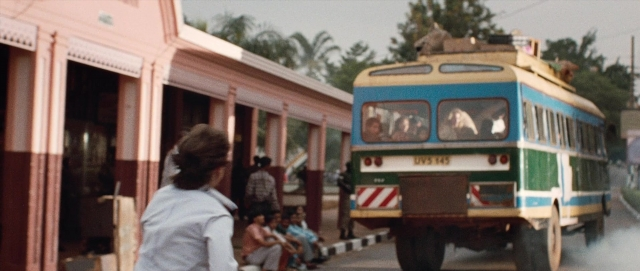 Wide shot frame from The Last King of Scotland — sitting, street, bus