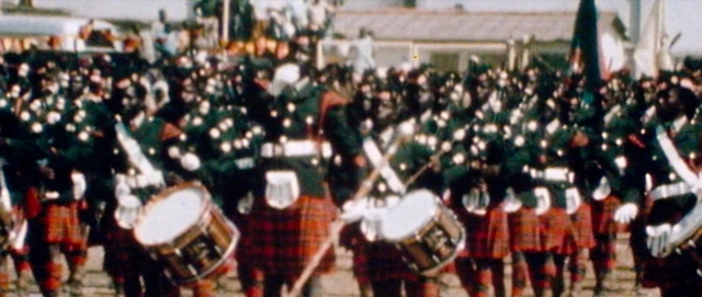 Wide shot frame from The Last King of Scotland — walking, street, drum