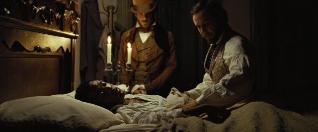 Wide shot frame from 12 Years a Slave — standing, room, bed