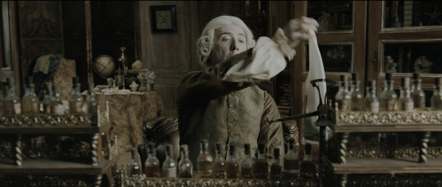 Wide shot frame from Perfume: The Story of a Murderer — sitting, coat, hand