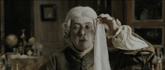 Wide shot frame from Perfume: The Story of a Murderer — table, coat, hand