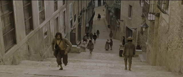 Wide shot frame from Perfume: The Story of a Murderer — walking, street, bag