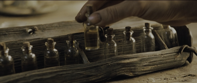 Wide shot frame from Perfume: The Story of a Murderer — hand, bottle, glass