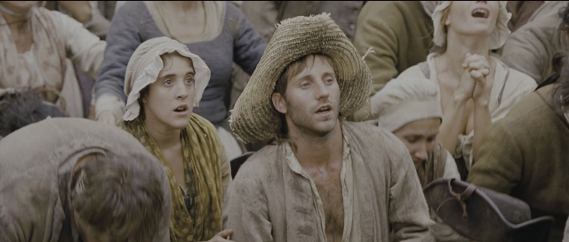Wide shot frame from Perfume: The Story of a Murderer — sitting, dialogue, hat
