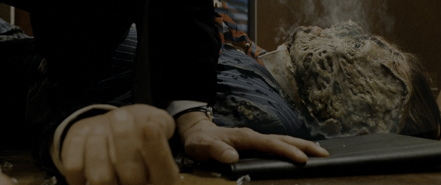 Wide shot frame from Constantine — room, table, suit