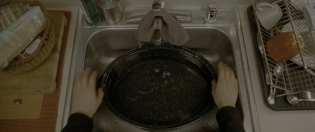 Wide shot frame from Constantine — kitchen, person, frying pan