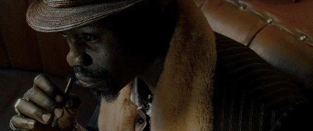 Wide shot frame from Constantine — room, hat, hand
