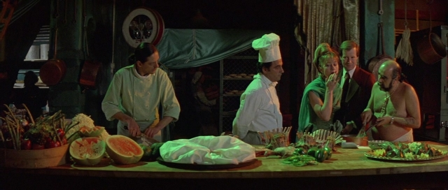 Wide shot frame from The Cook, the Thief, His Wife & Her Lover — standing, plate, table