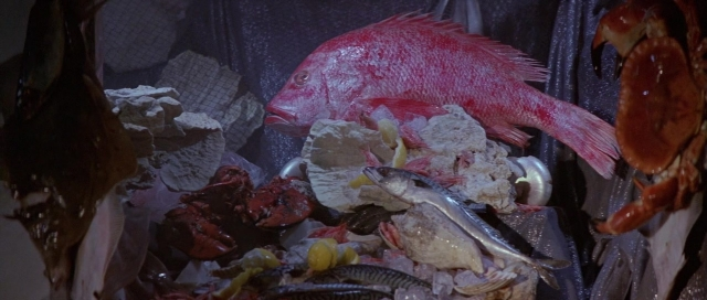 Wide shot frame from The Cook, the Thief, His Wife & Her Lover — bed, fish