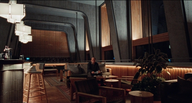 Wide shot frame from Dream Scenario — sitting, room, table