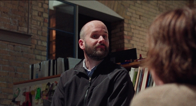 Wide shot frame from Dream Scenario — standing, room, beard