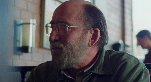 Medium shot frame from Dream Scenario — sitting, room, table