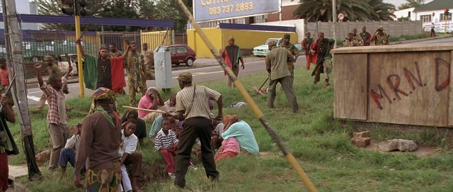 Wide shot frame from Hotel Rwanda — street, person, human face