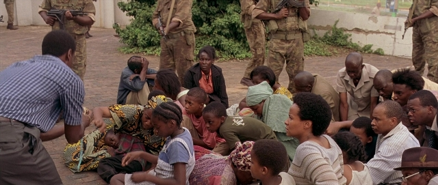 Wide shot frame from Hotel Rwanda — sitting, standing, dialogue