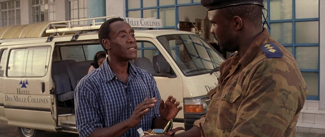 Wide shot frame from Hotel Rwanda — standing, dialogue, hat