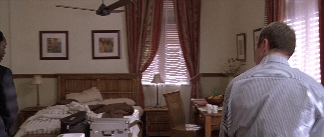 Wide shot frame from Hotel Rwanda — standing, room, table