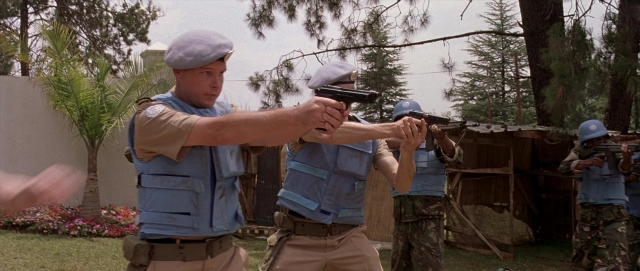 Wide shot frame from Hotel Rwanda — standing, hat, hand