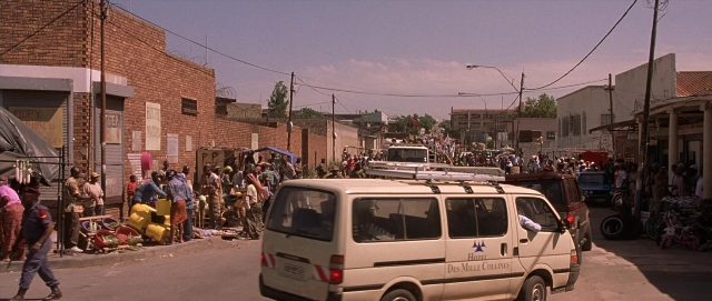 Wide shot frame from Hotel Rwanda — walking, street, van