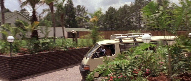 Wide shot frame from Hotel Rwanda — street, house, land vehicle