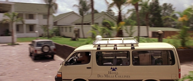 Wide shot frame from Hotel Rwanda — sitting, street, car