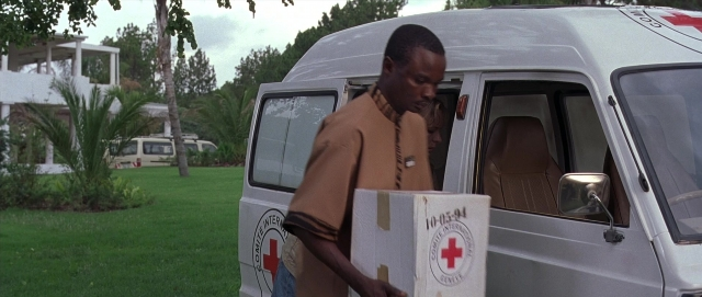 Medium shot frame from Hotel Rwanda — standing, door, shirt