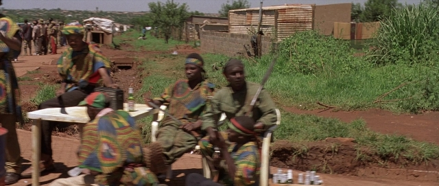 Wide shot frame from Hotel Rwanda — sitting, standing, dialogue