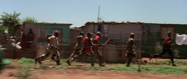 Wide shot frame from Hotel Rwanda — sitting, standing, street