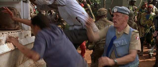 Wide shot frame from Hotel Rwanda — standing, street, hat