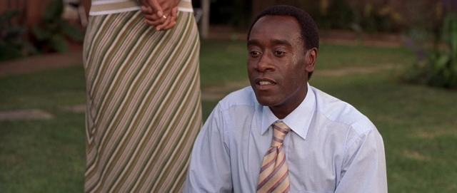 Medium shot frame from Hotel Rwanda — sitting, tie, shirt