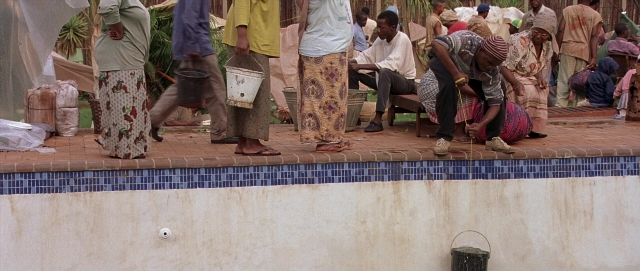 Wide shot frame from Hotel Rwanda — sitting, standing, person
