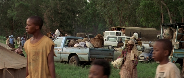 Wide shot frame from Hotel Rwanda — tent, wheel, person