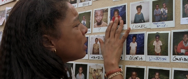 Wide shot frame from Hotel Rwanda — standing, room, hand