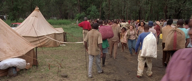 Wide shot frame from Hotel Rwanda — walking, car, tent