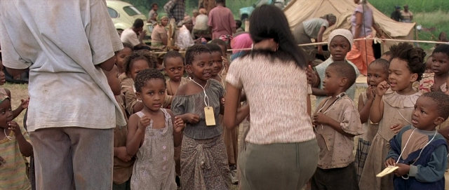 Wide shot frame from Hotel Rwanda — sitting, standing, car