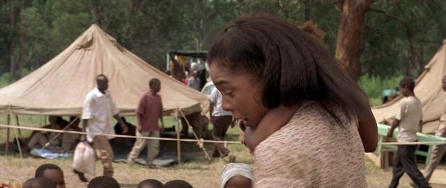 Wide shot frame from Hotel Rwanda — sitting, standing, tent