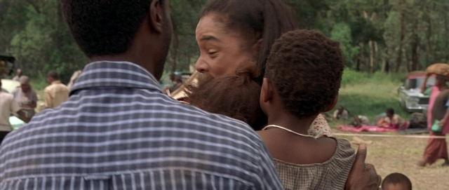 Wide shot frame from Hotel Rwanda — standing, shirt, face