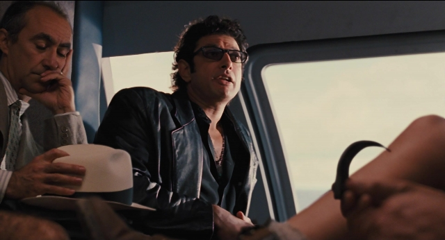 Medium shot frame from Jurassic Park — sitting, hand, suit