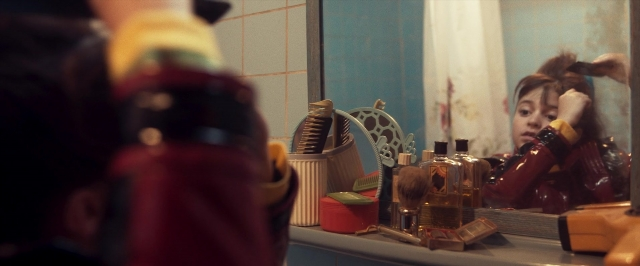 Wide shot frame from The Persian Version — sitting, mirror, hand